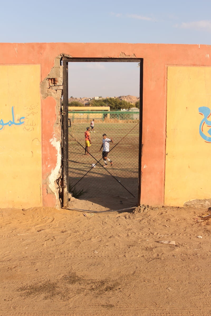 Young boys playing football on a dirt field
