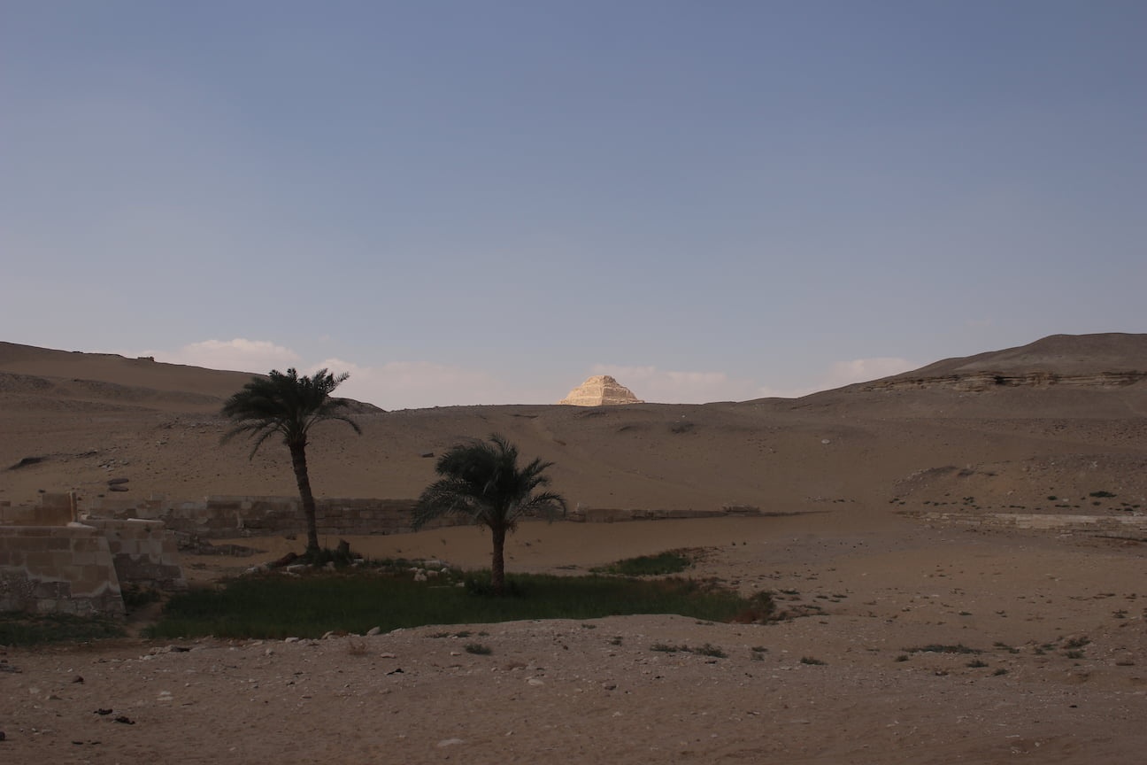 Djoser Pyramid seen from a distance, partially hidden behind a dune
