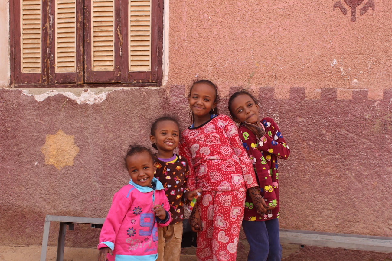 Four young girls dressed in colorful pajamas playfully posing for the camera