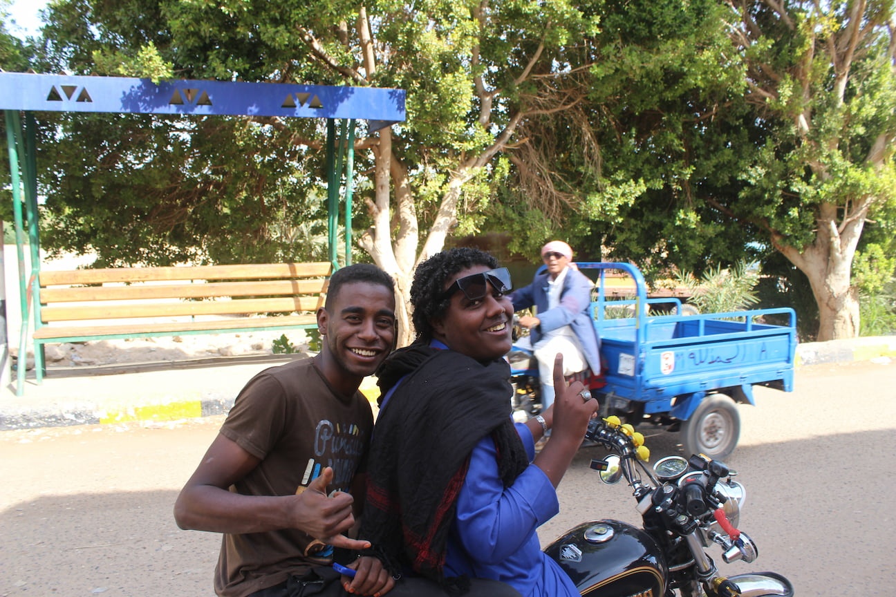 Two boys driving a motorbike stop and pose for the camera