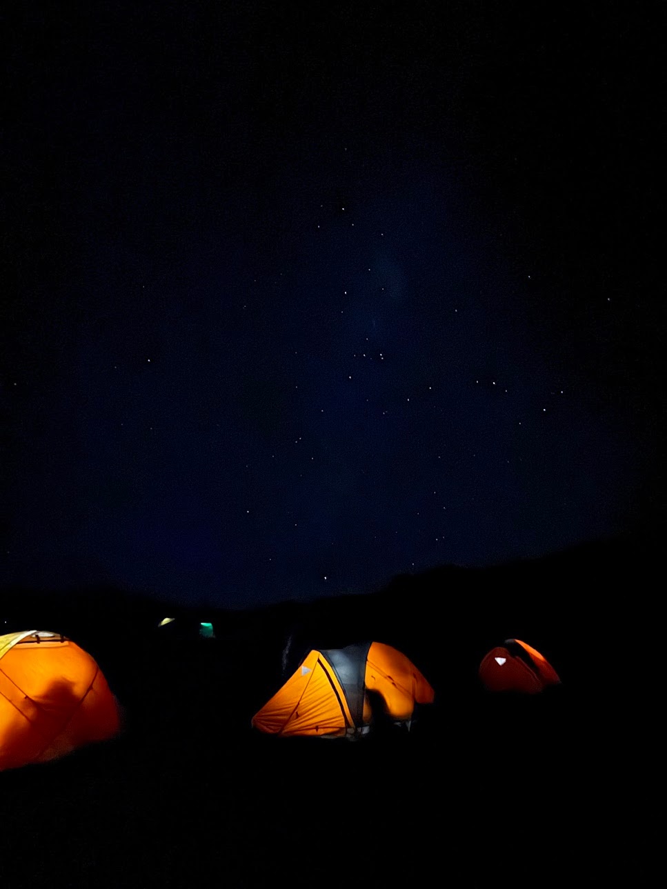 Campsite with lit-up tents under the night sky